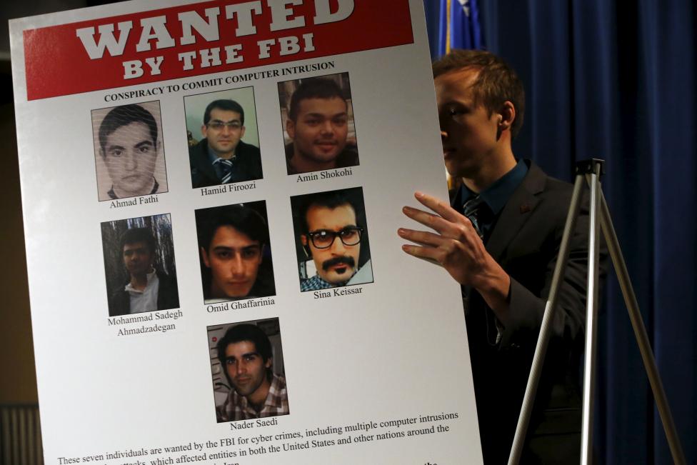 An aide unveils a wanted poster before Lynch and Comey hold a news conference to announce indictments on Iranian hackers at the Justice Department in Washington